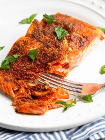 Blackened salmon on a plate flaked with a fork.