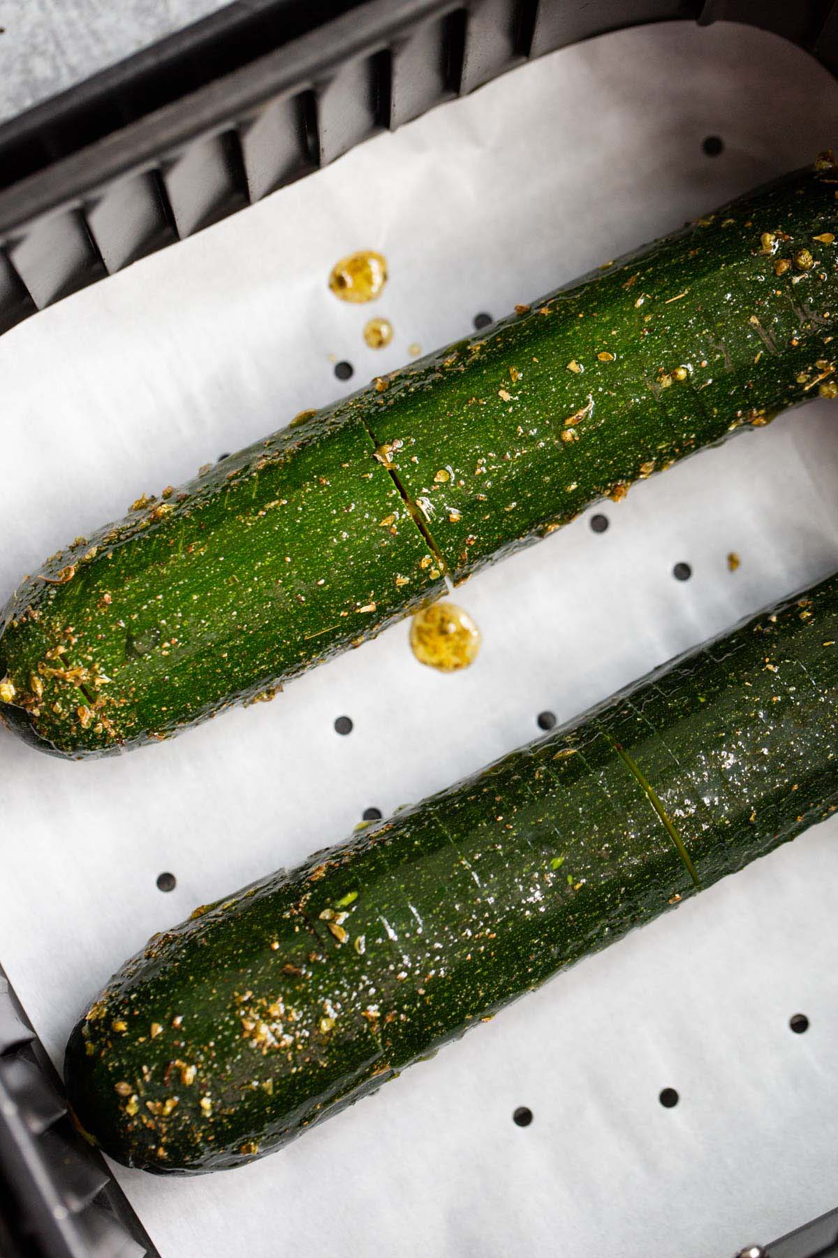 Uncooked zucchini in air fryer basket.