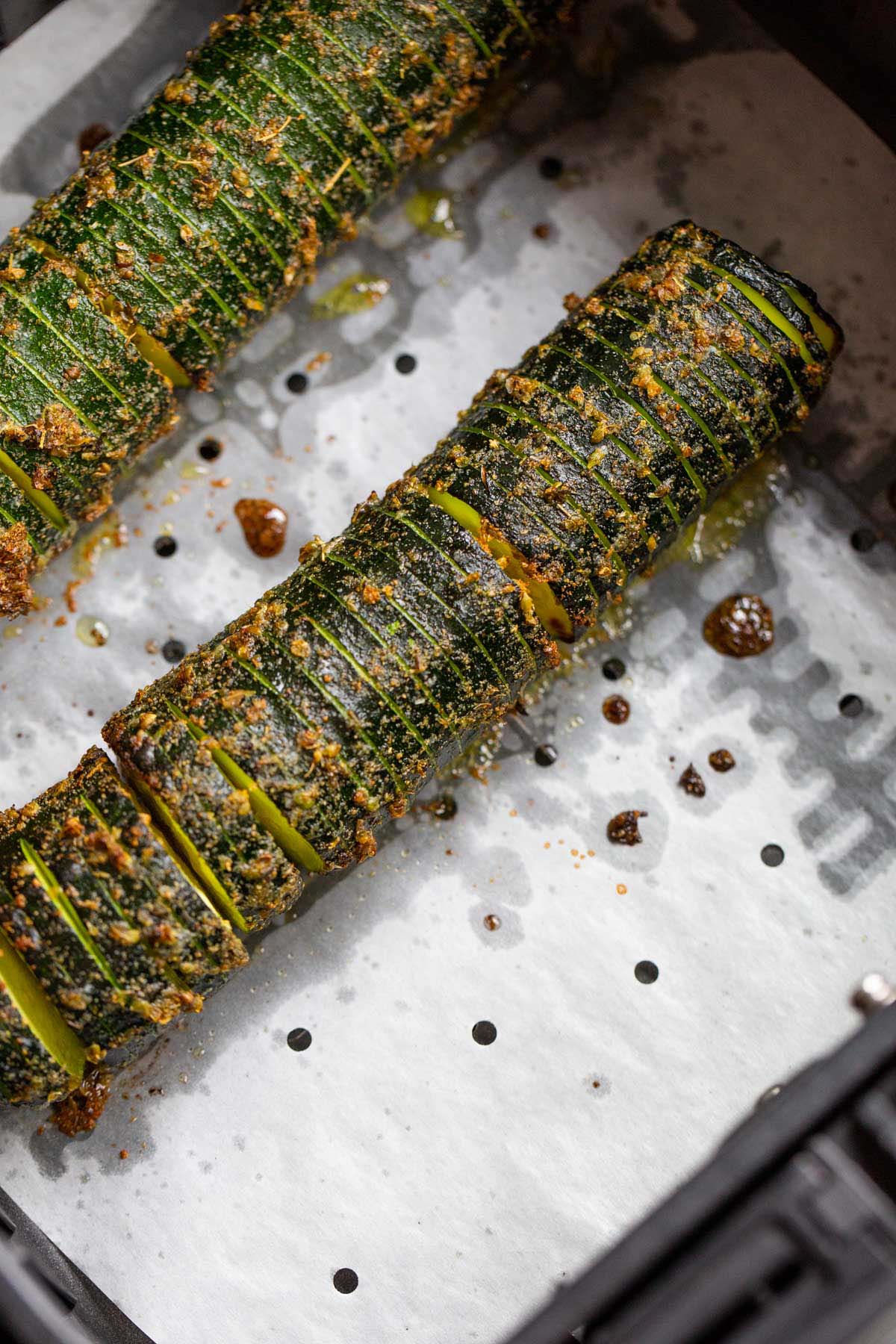 Air fried hasselback zucchini in air fryer basket.