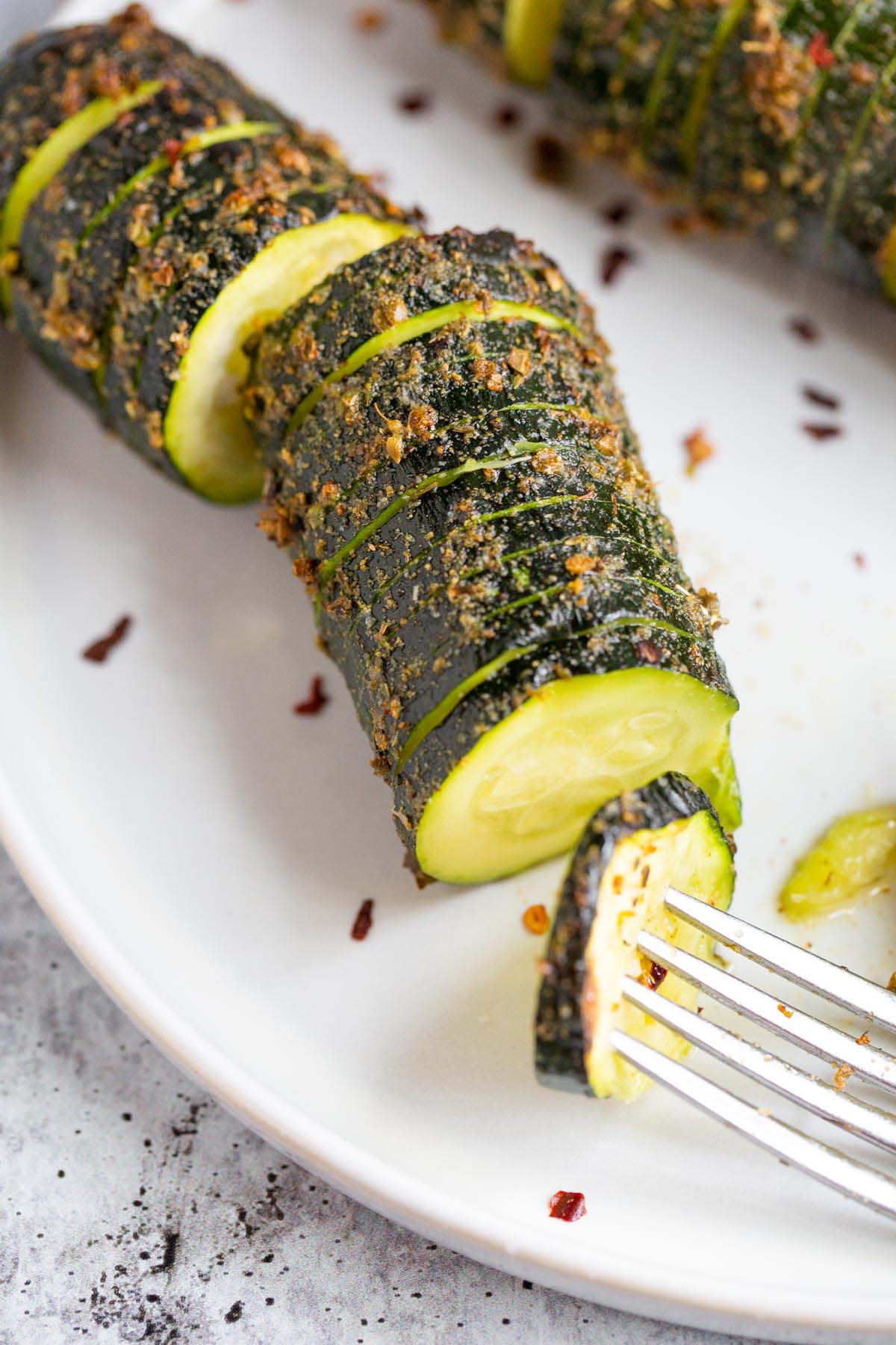 Air fried hasselback zucchini on a plate up close.