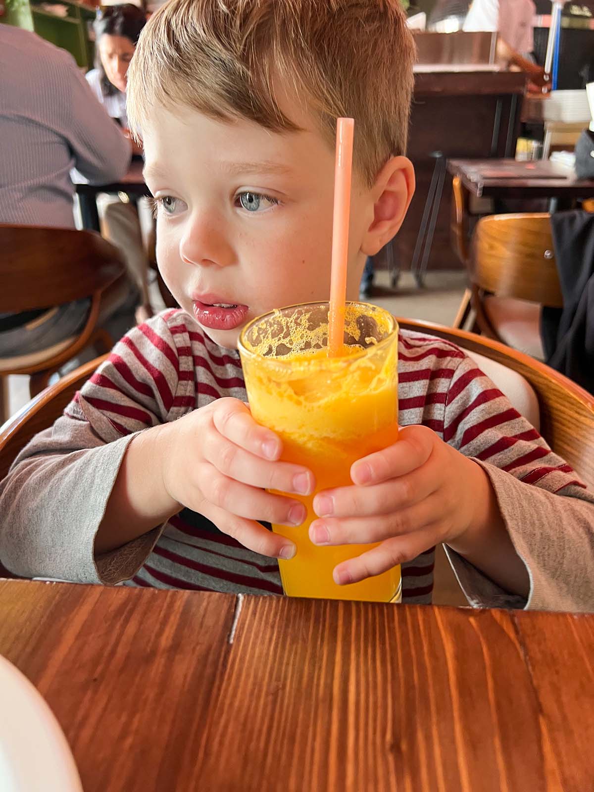 Young boy drinking orange juice