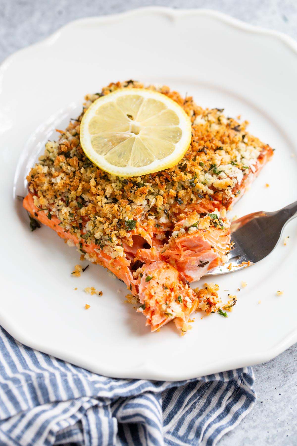 Panko crusted salmon on a plate with a lemon slice.