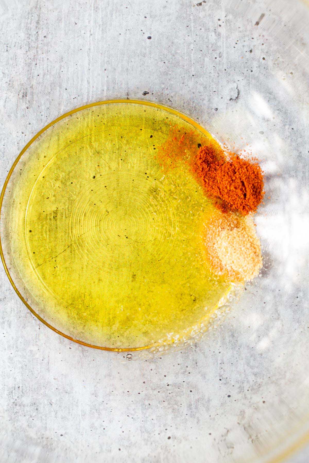 Olive oil, salt, garlic powder, and paprika in a bowl.