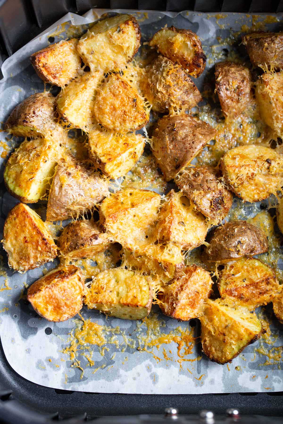 Air fryer parmesan potatoes in the air fryer basket.