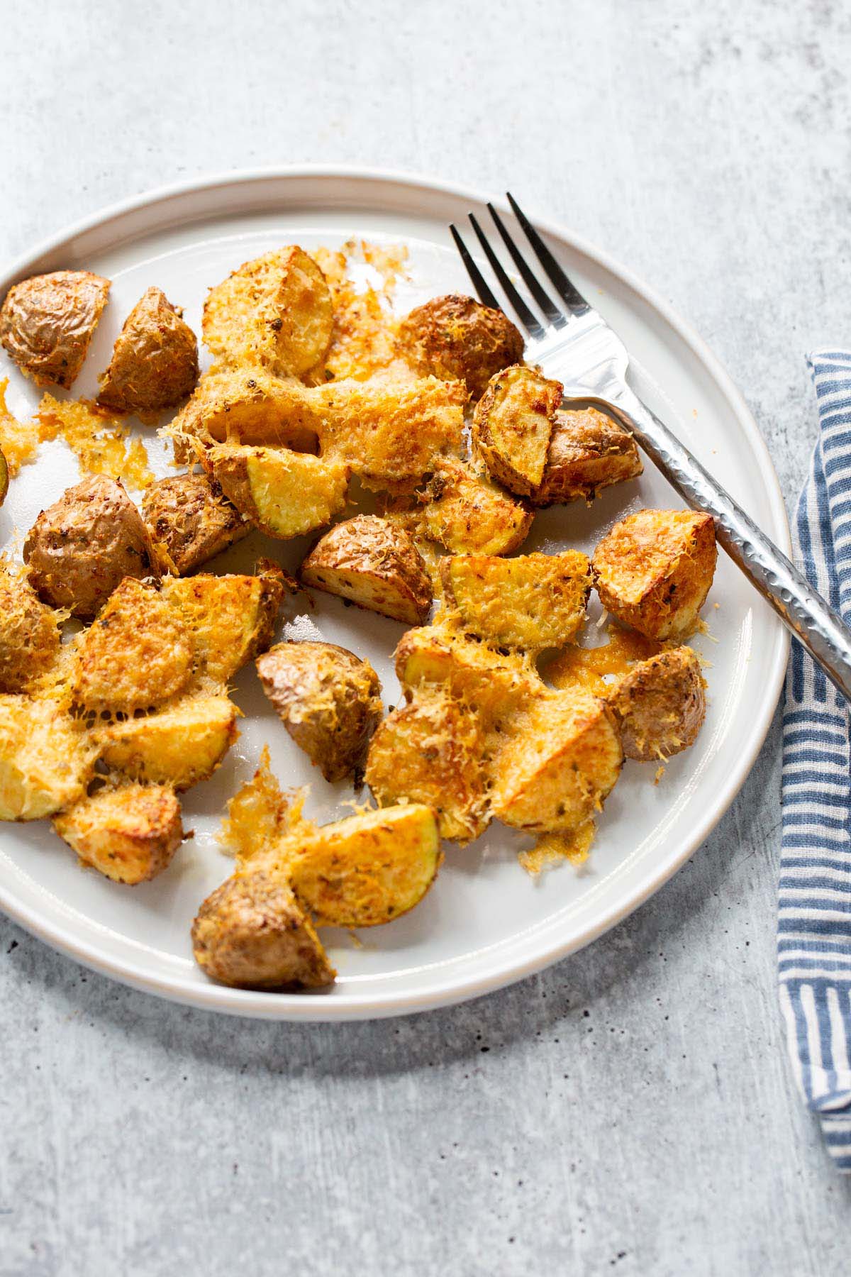 Air fryer parmesan potatoes on a white plate with a fork.