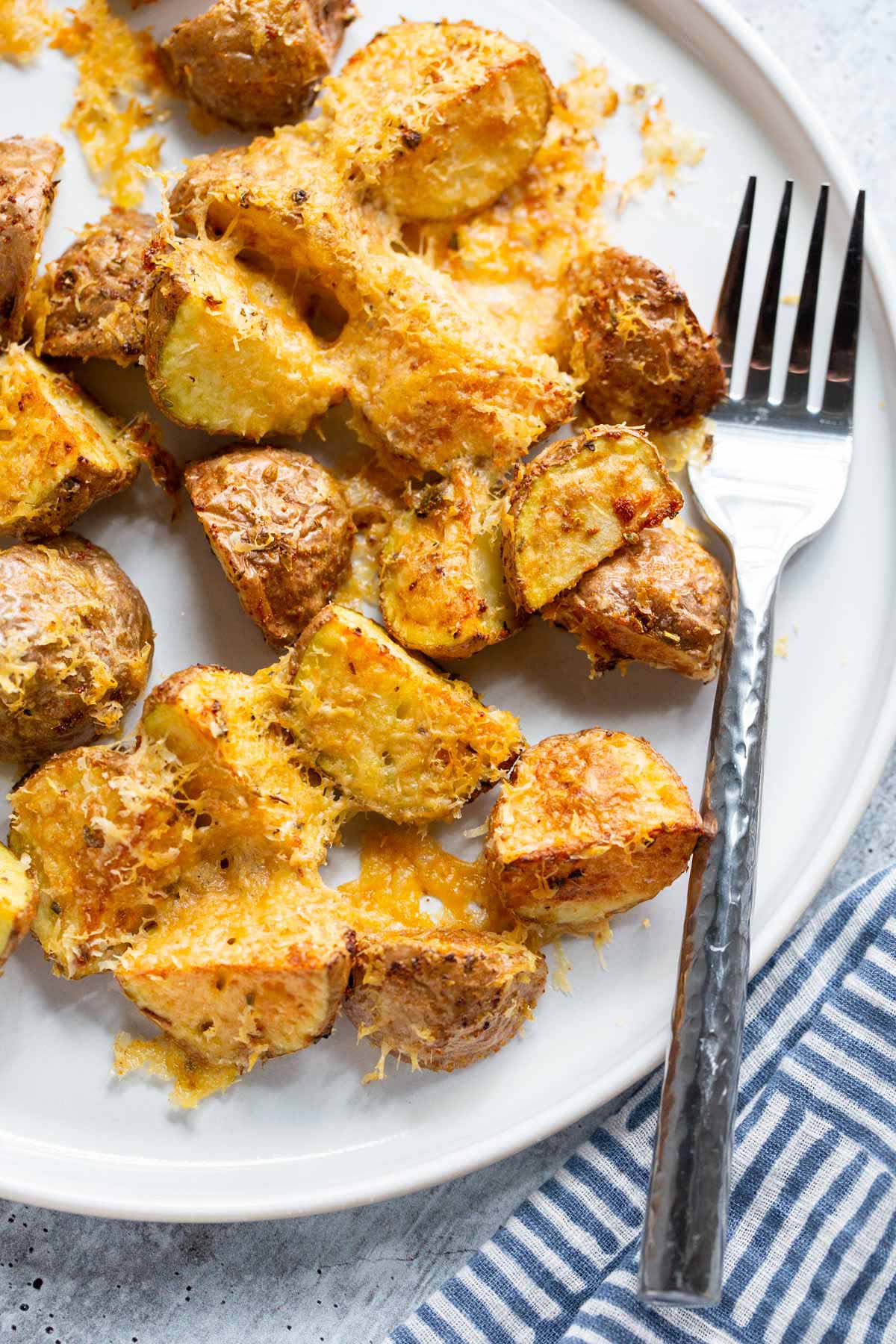 Air fryer parmesan potatoes on a white plate with a fork.