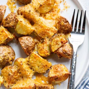 Parmesan potatoes on a plate with a fork.