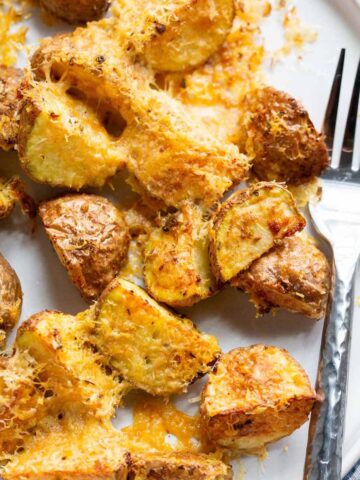 Parmesan potatoes on a plate with a fork.