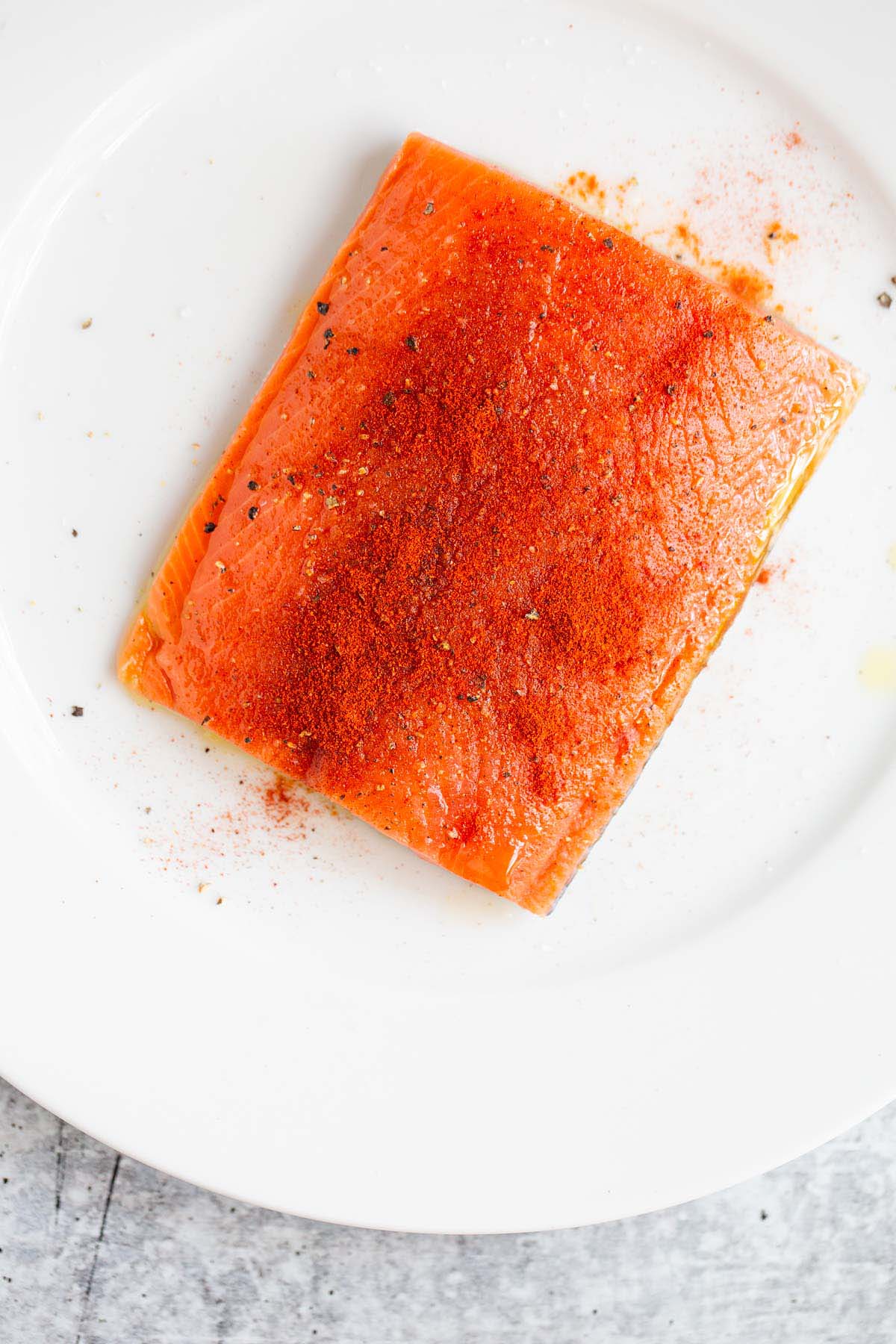 Salmon fillet seasoned with salt, pepper, and paprika.