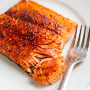 Air Fryer Sockeye Salmon flaked on a plate with a fork on the side.