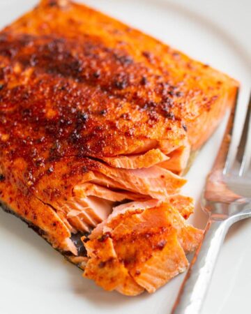 Air Fryer Sockeye Salmon flaked on a plate with a fork on the side.