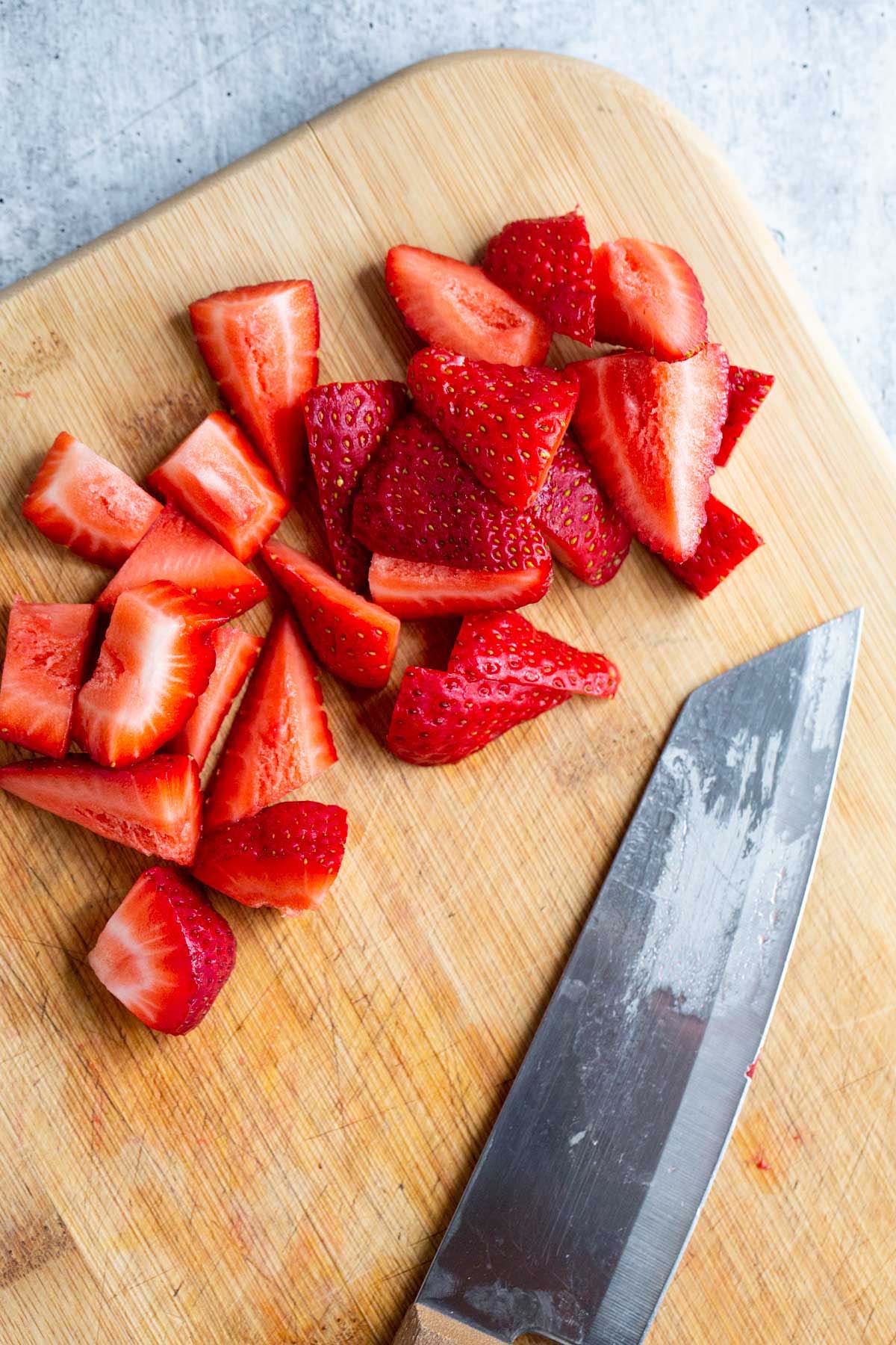 Strawberries sliced on a cutting board.
