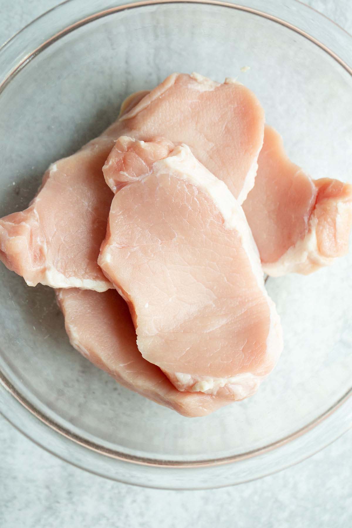 Raw pork chops in a bowl.