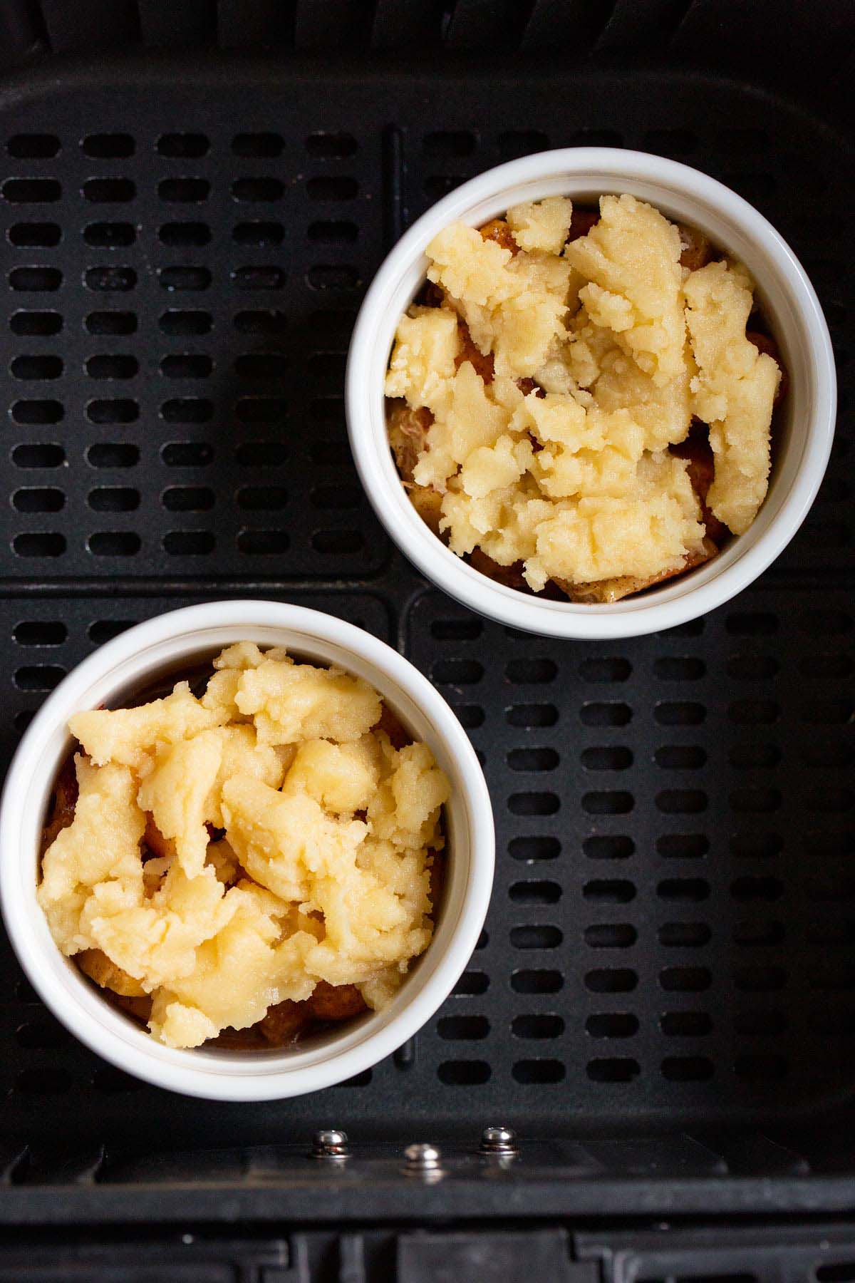 Uncooked peach cobbler in air fryer basket.