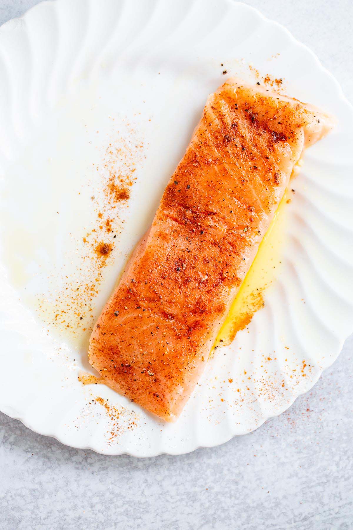 Seasoned uncooked salmon on a plate.