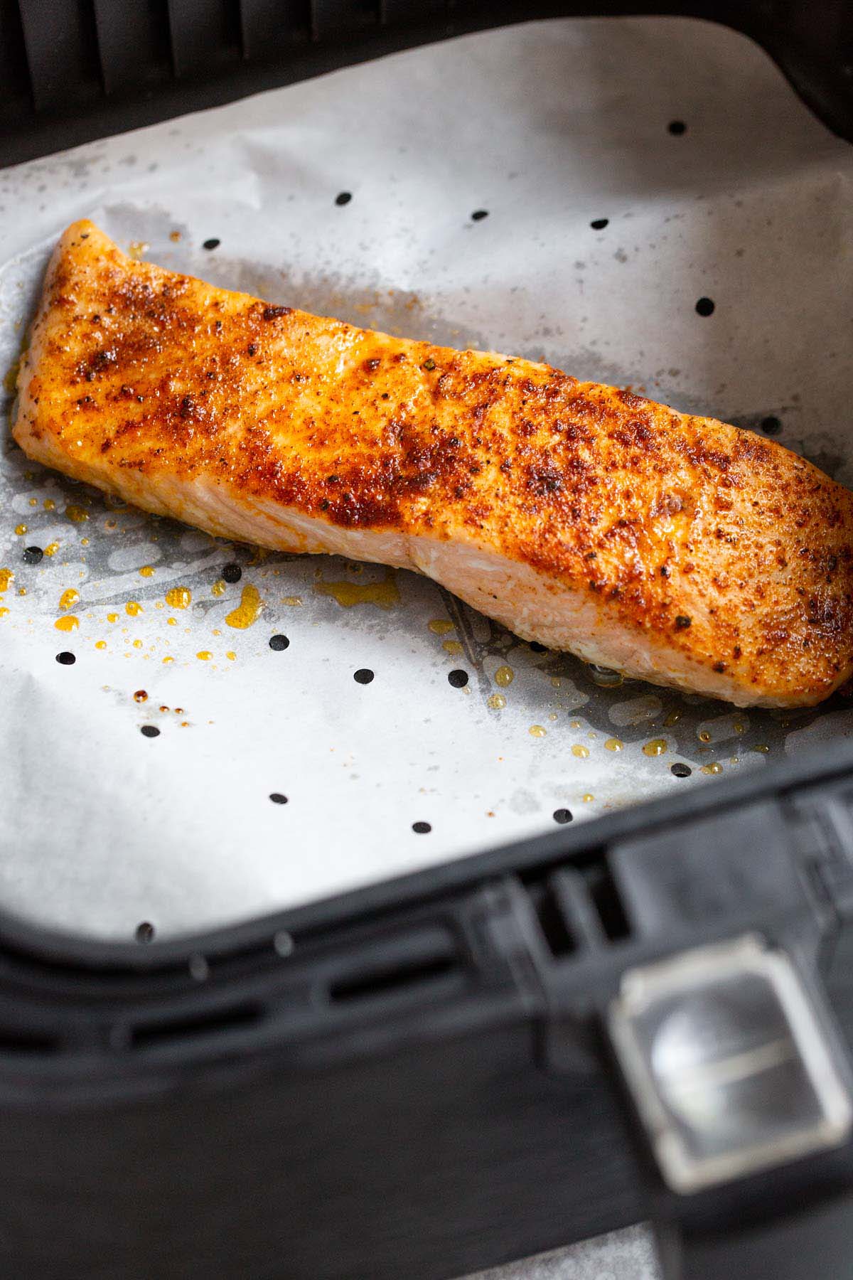 Cooked salmon in air fryer basket.