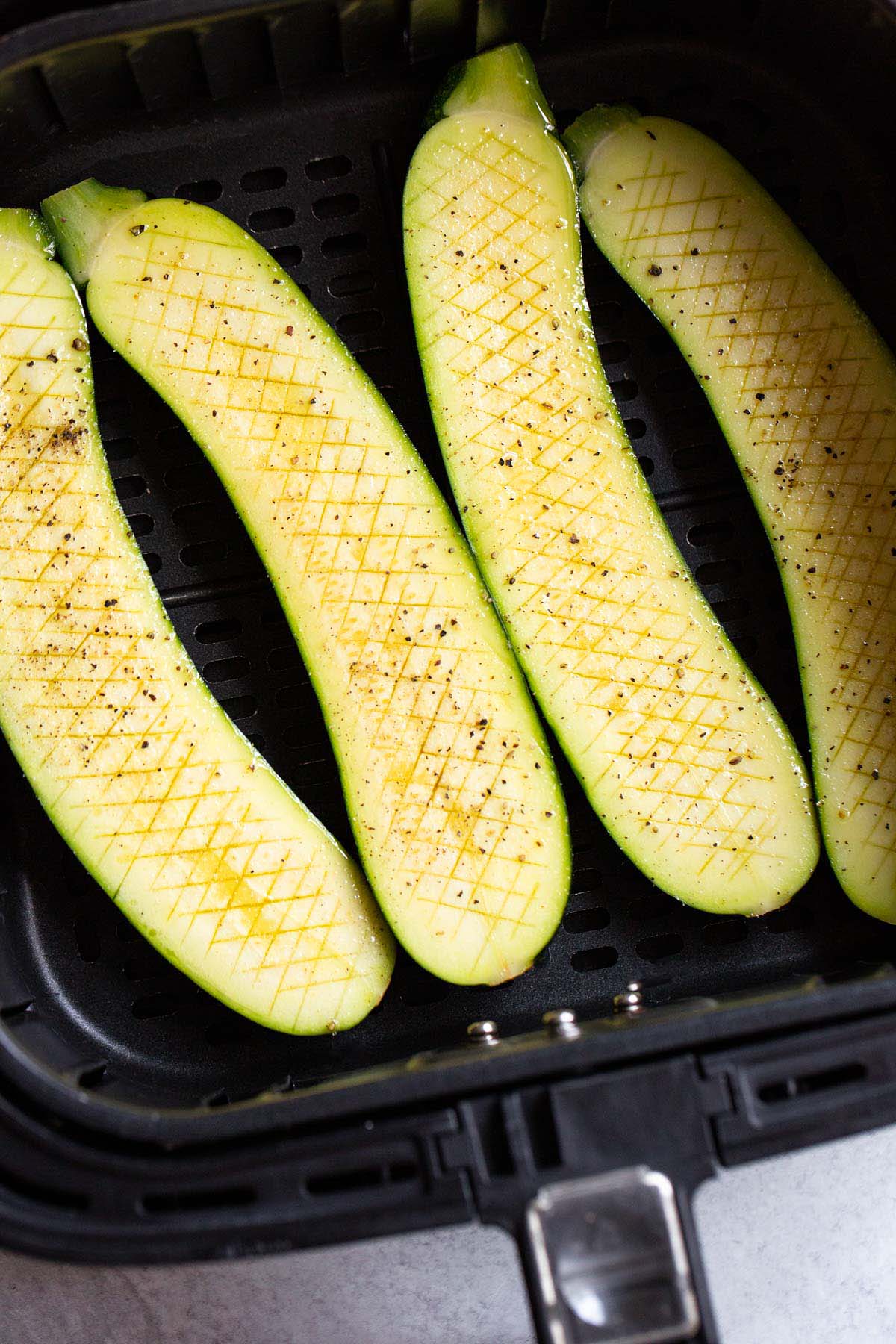 Crisscross zucchini in air fryer basket.