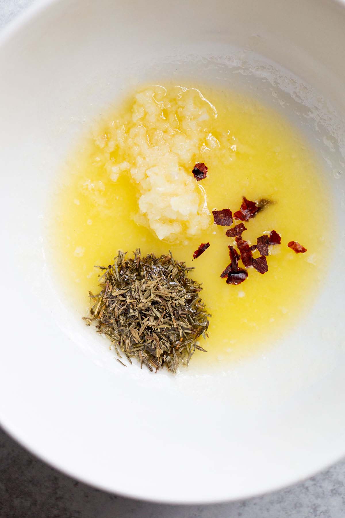 Herbs in a bowl with melted butter.