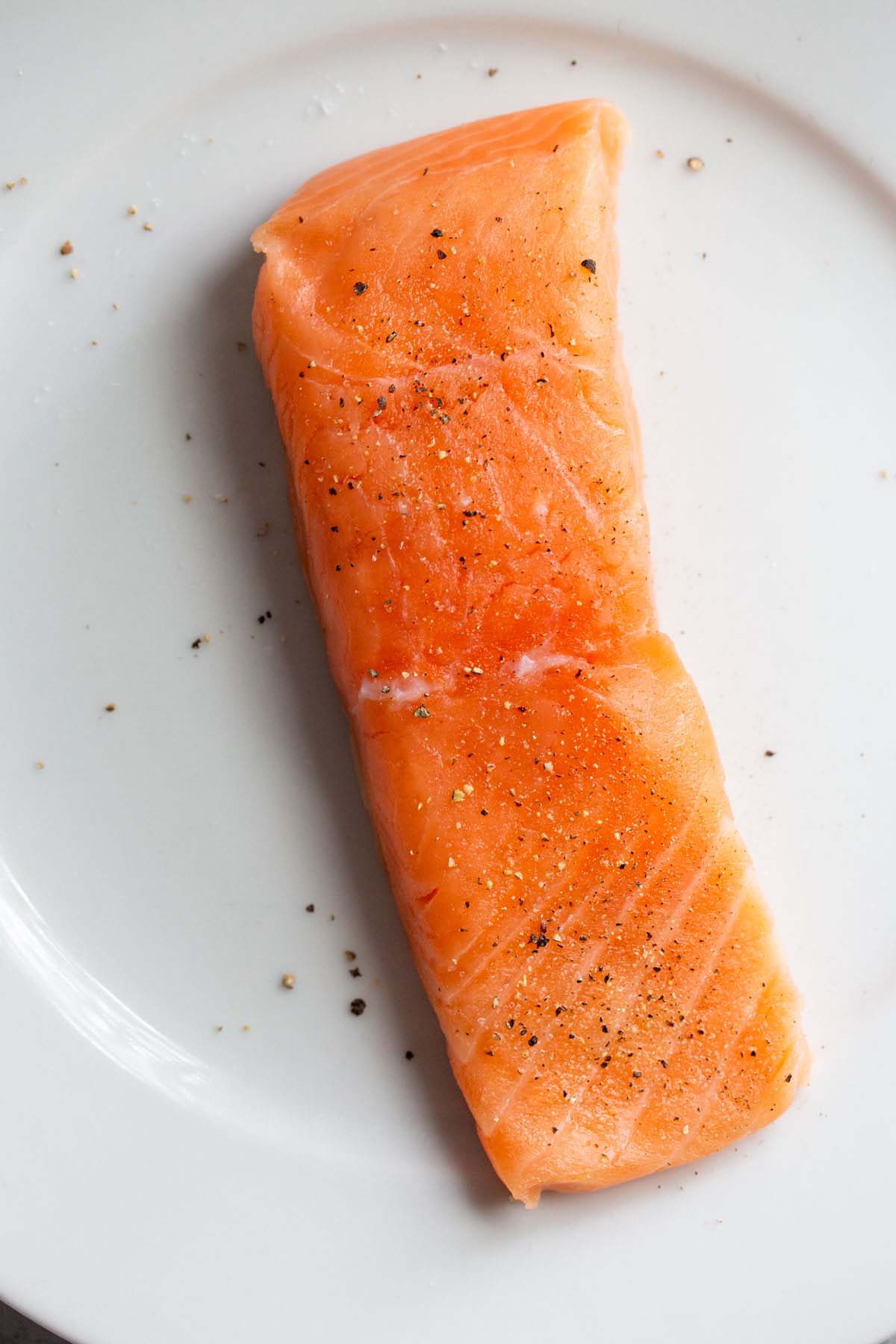 Salmon on a plate seasoned with salt and pepper.