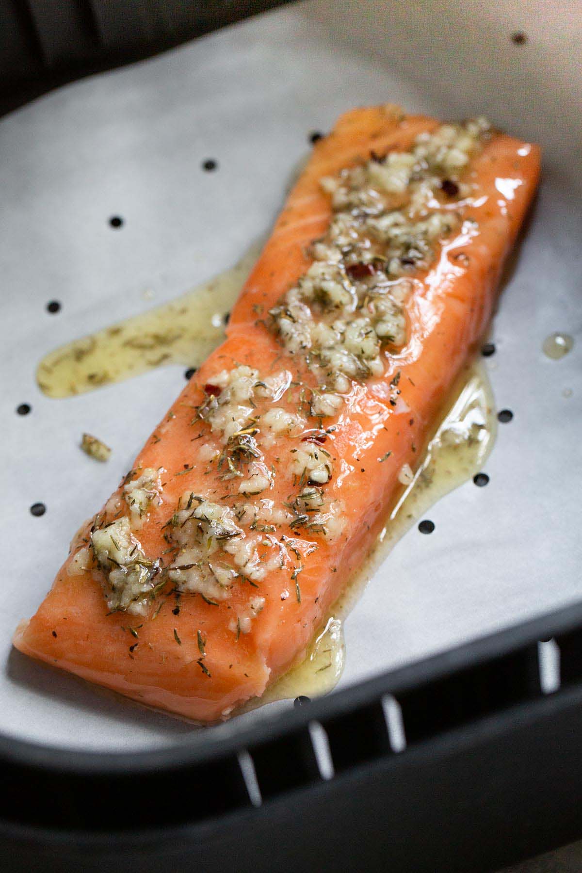 Uncooked salmon in air fryer basket.