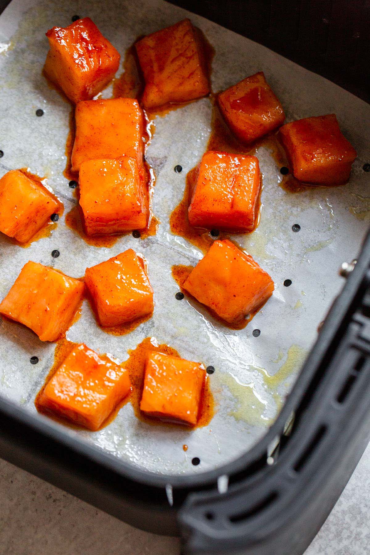 Uncooked salmon bites n air fryer basket.