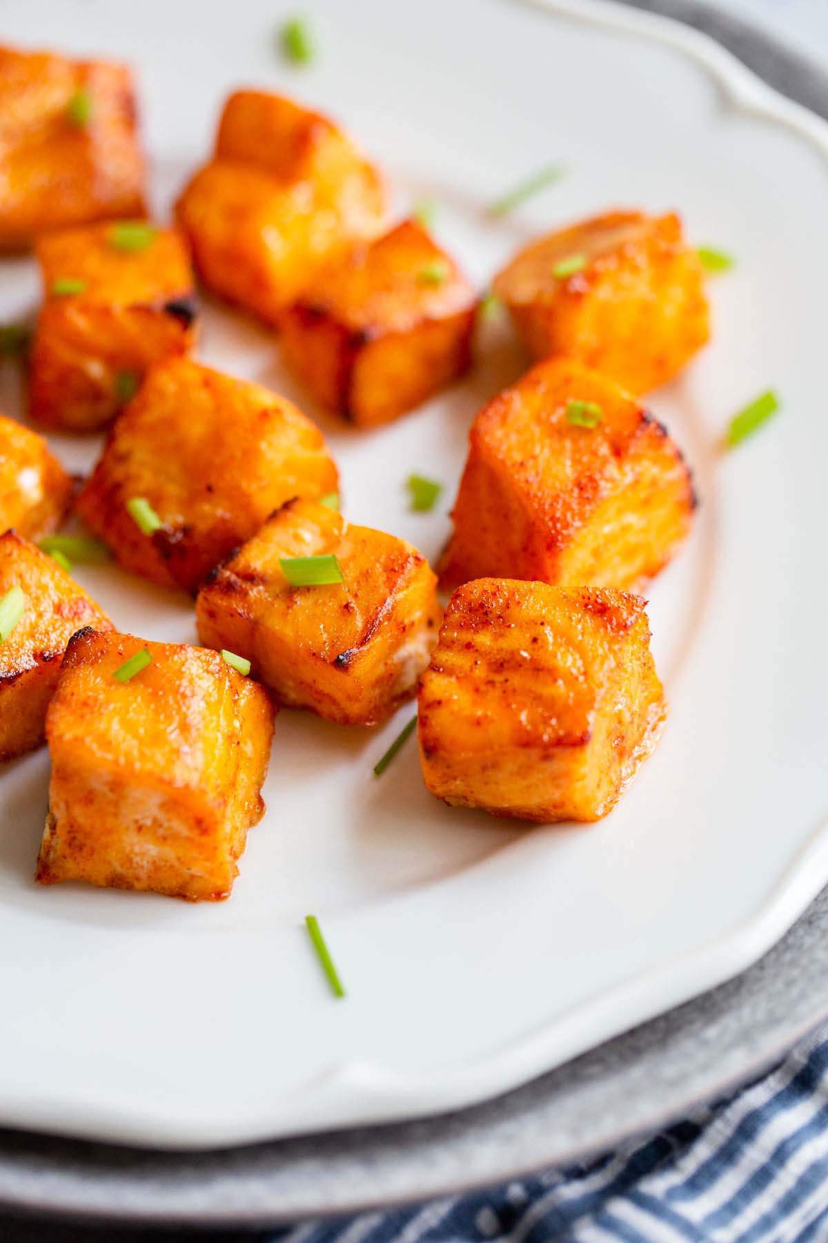 Salmon bites on a white plate up close.