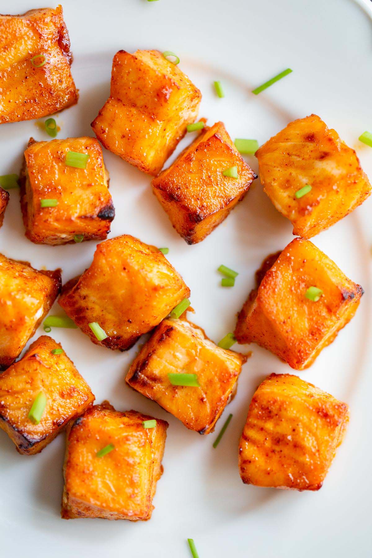 Salmon bites on a white plate up close.