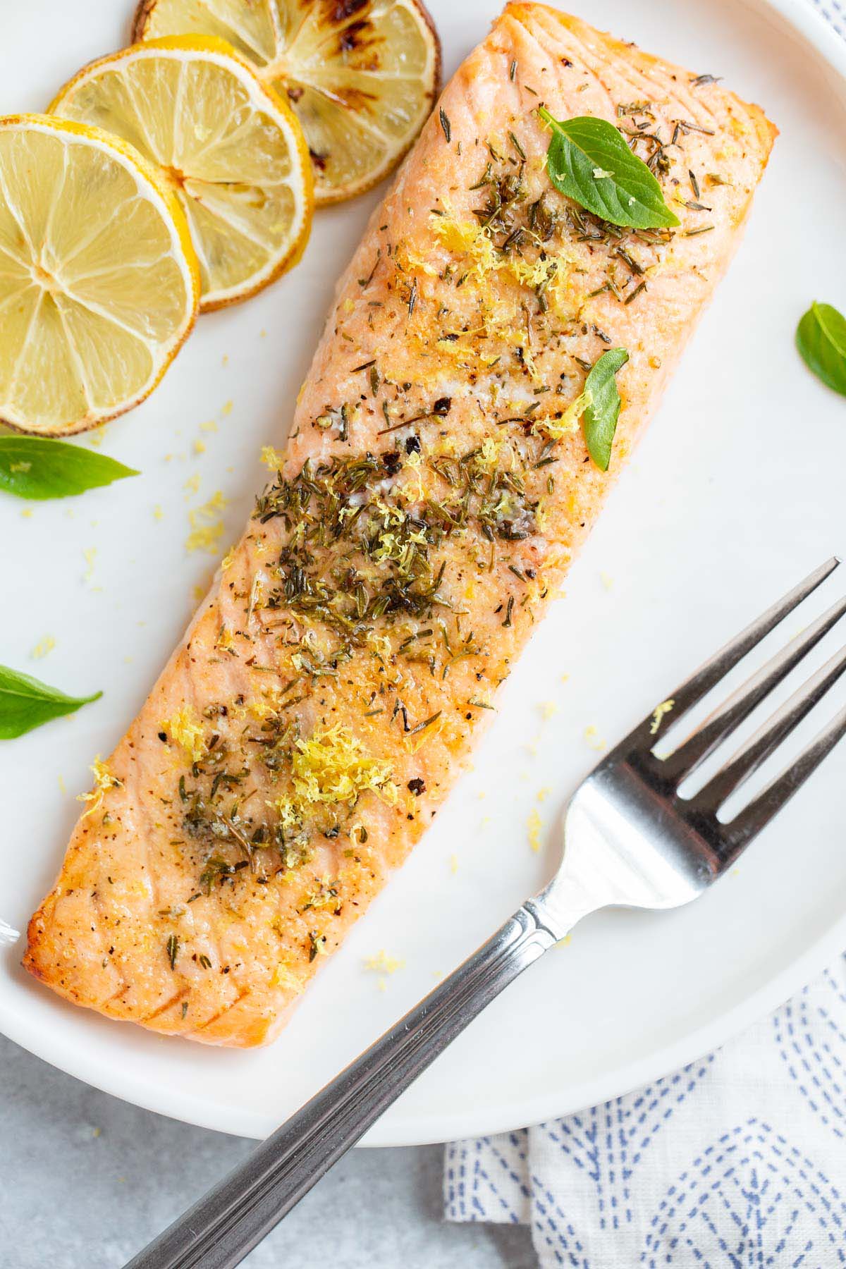 Air fried lemon garlic salmon on a plate with basil leaves.