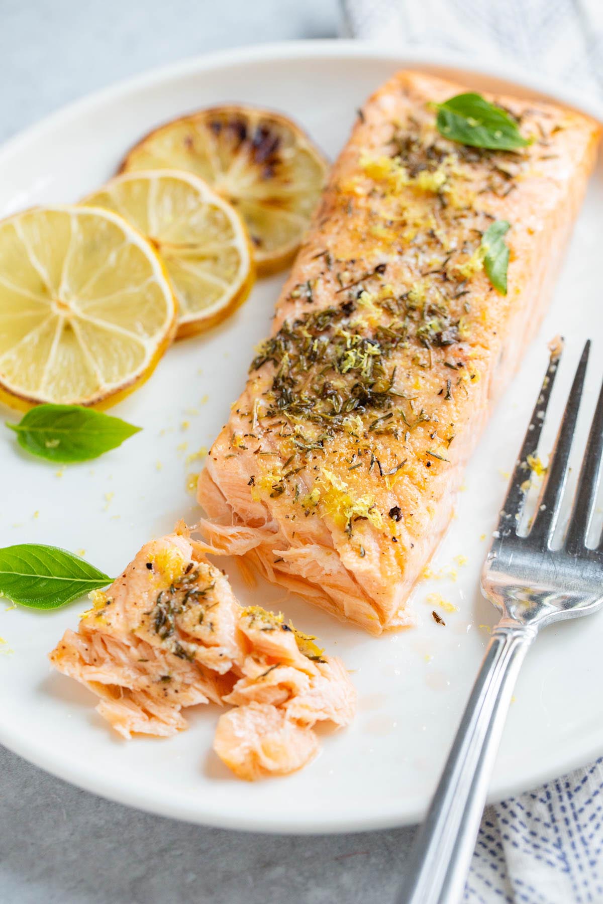 Air fried lemon garlic salmon on a plate with basil leaves.