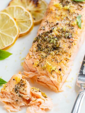 Air fried lemon garlic salmon on a plate with basil leaves.