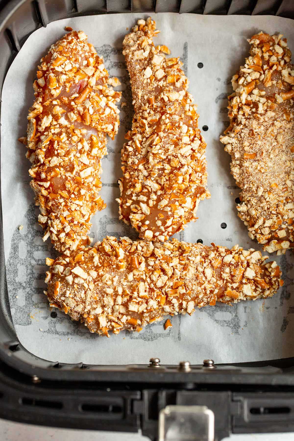 Uncooked chicken tenders in air fryer basket