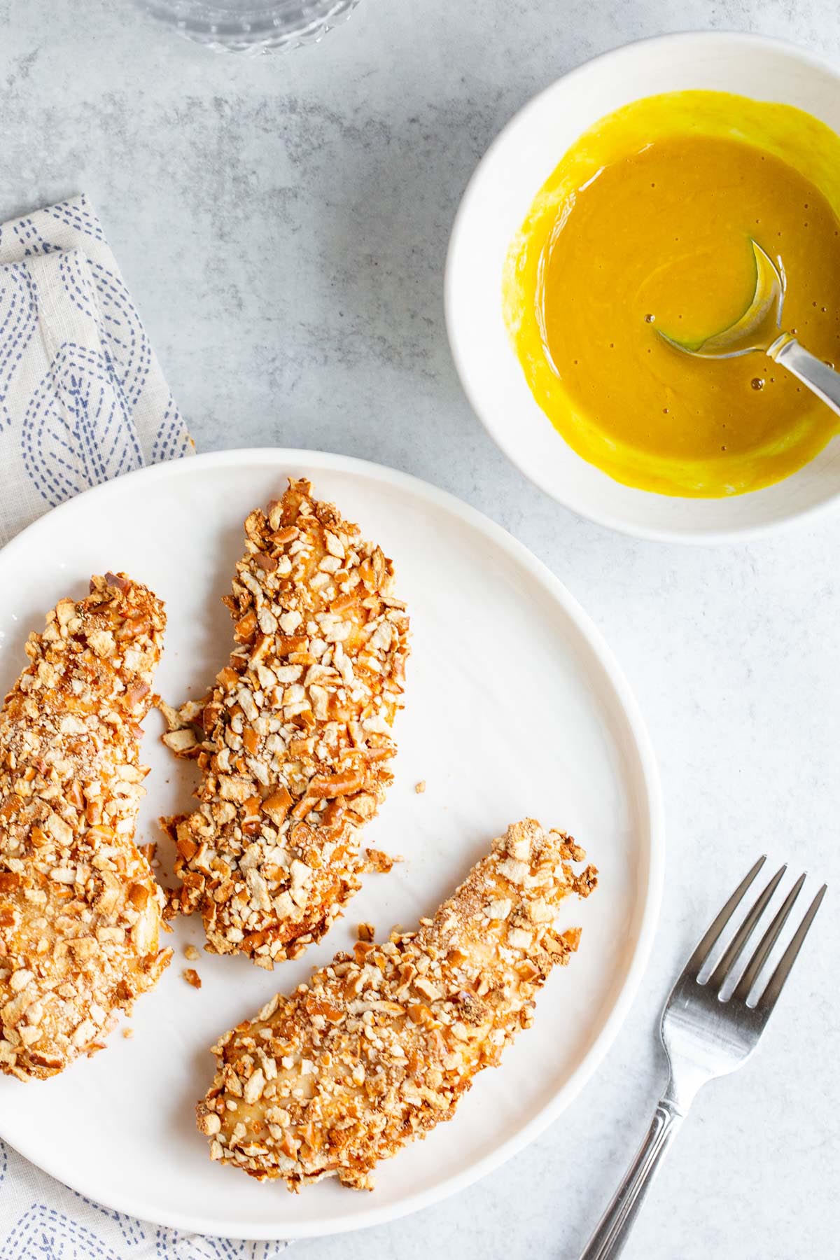 Air fryer pretzel chicken with honey mustard dipping sauce on the side.