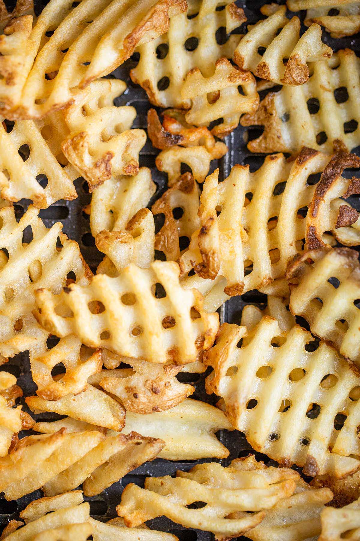 Waffle fries in air fryer basket.