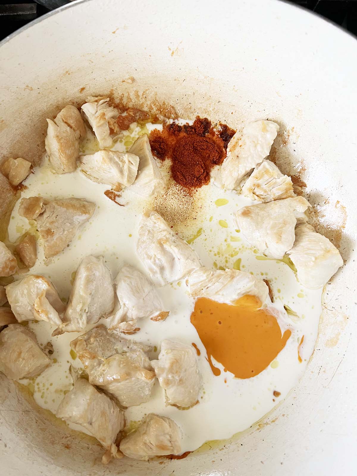 Adding spices and cream to chicken