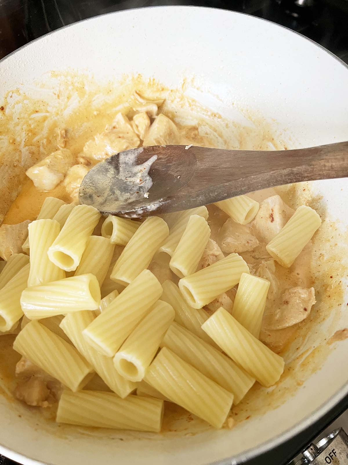 Mixing pasta into the peri peri sauce