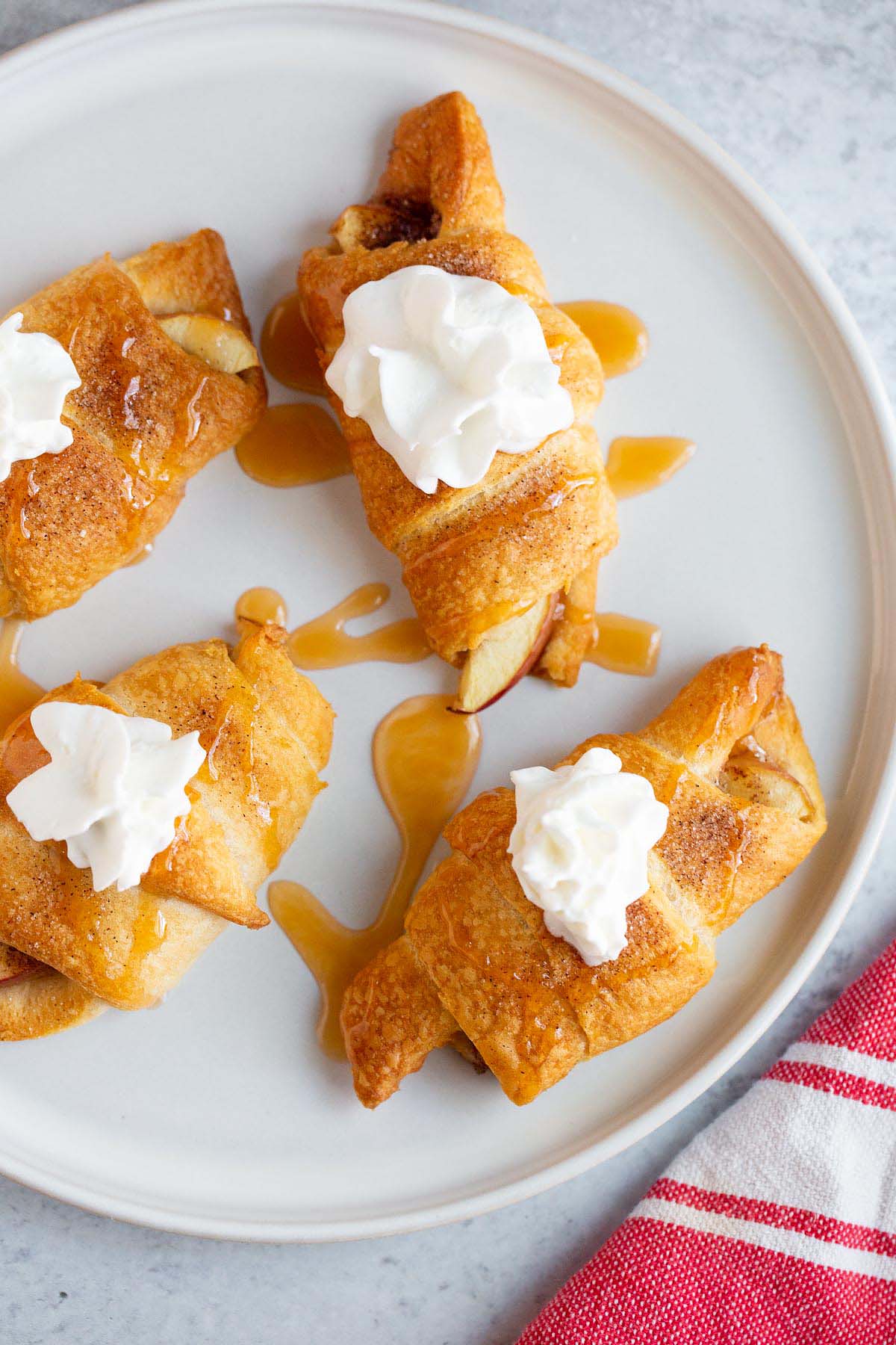 Apple pie crescent rolls on a plate with whipped cream.