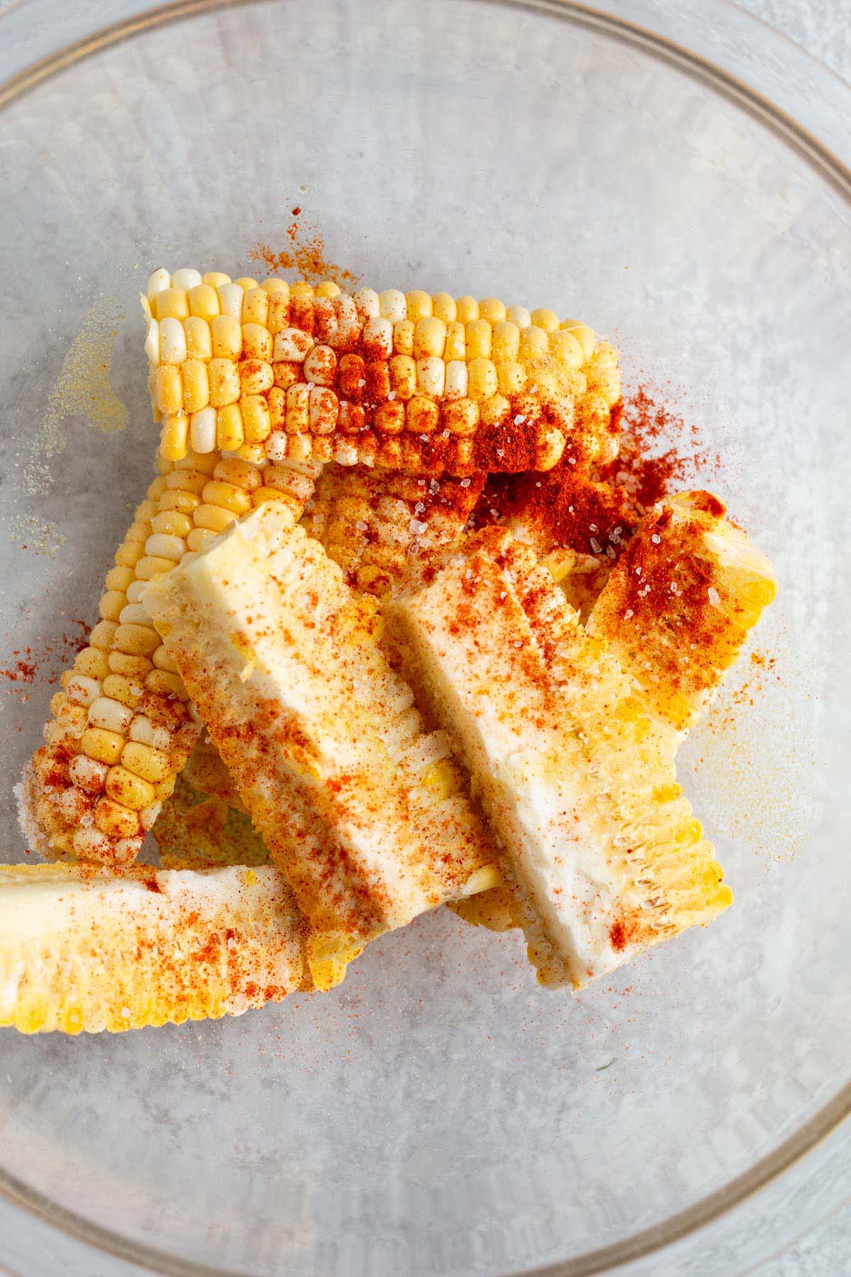 Corn ribs with seasonings in a large bowl.