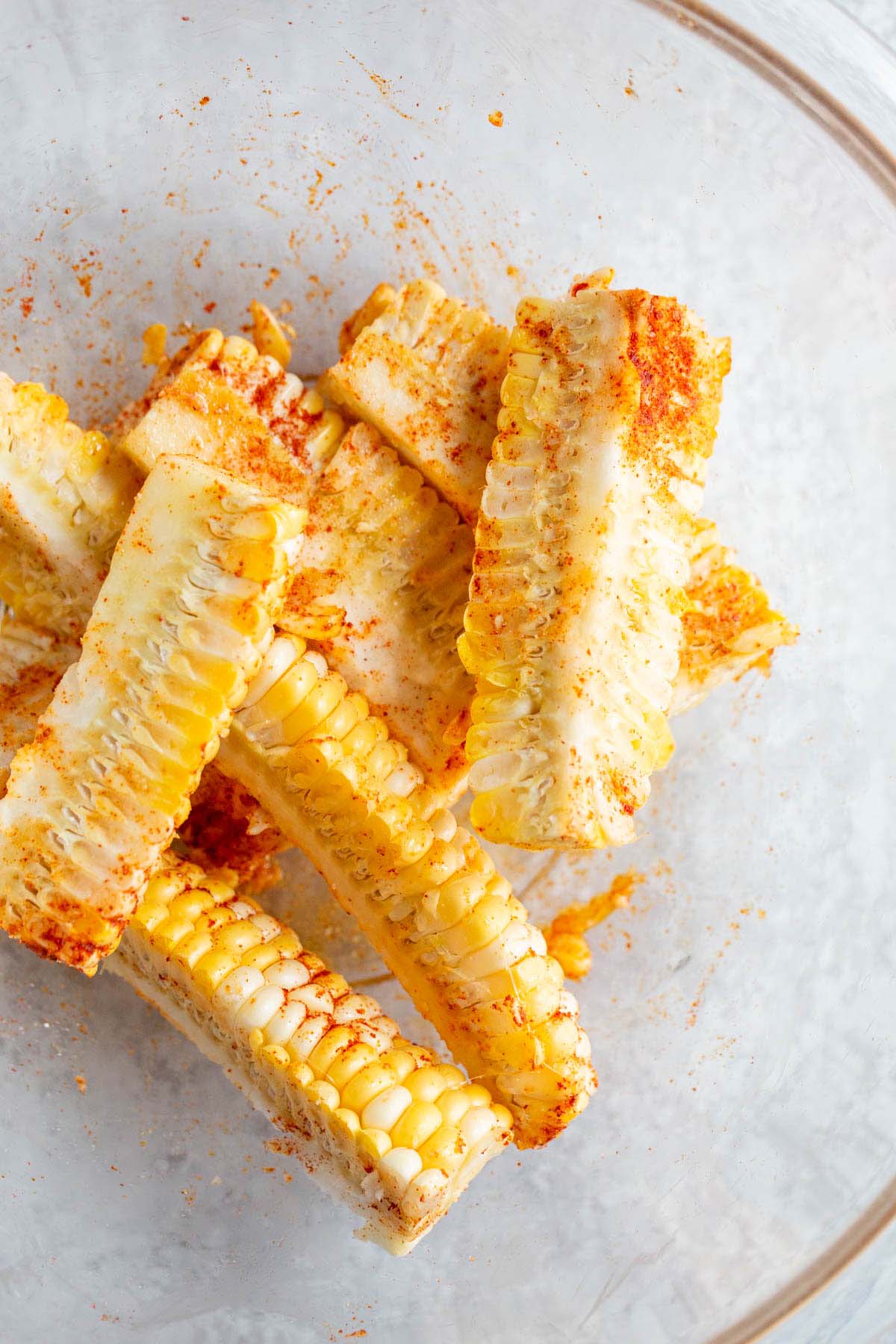 Corn ribs with seasonings in a large bowl.