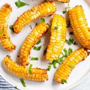 Corn ribs on a white plate with parsley.