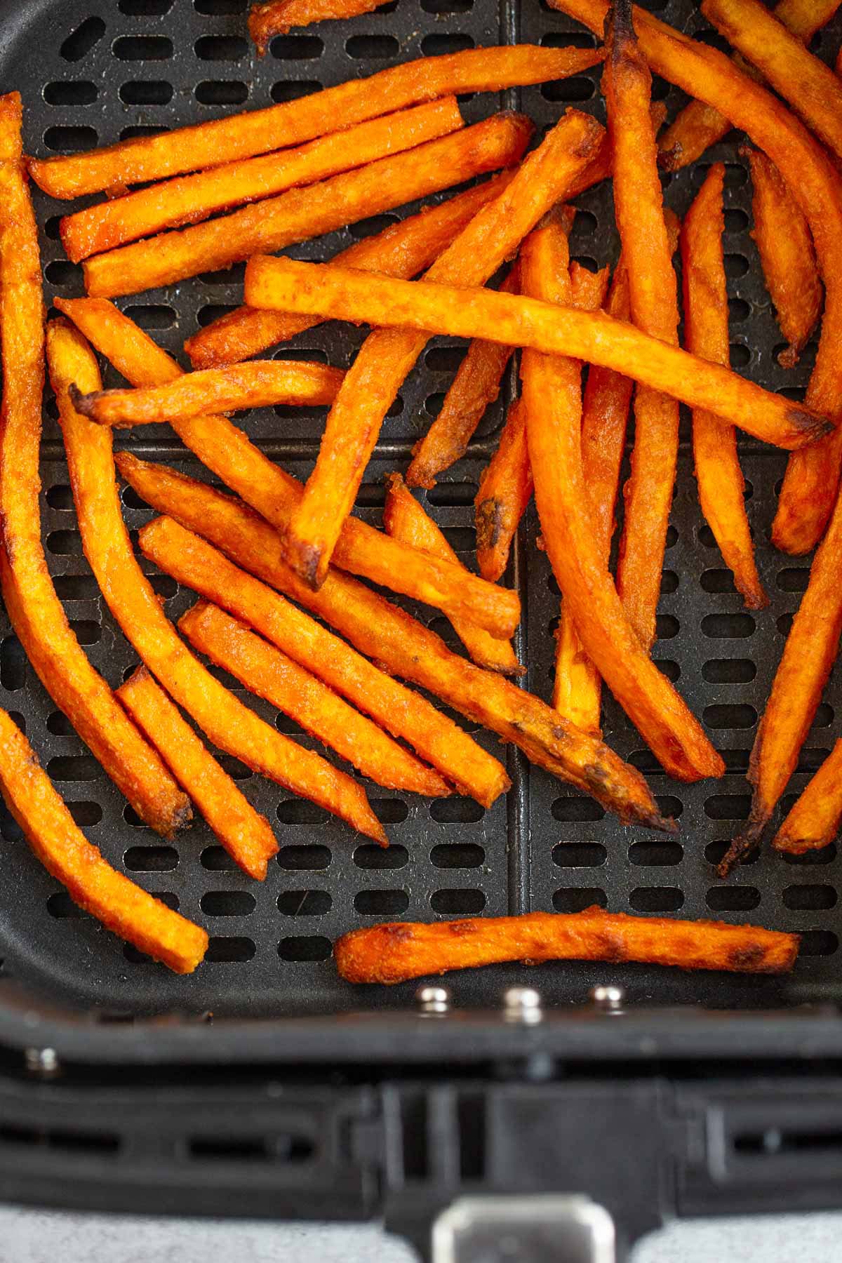 Cooked sweet potato fries in air fryer basket.
