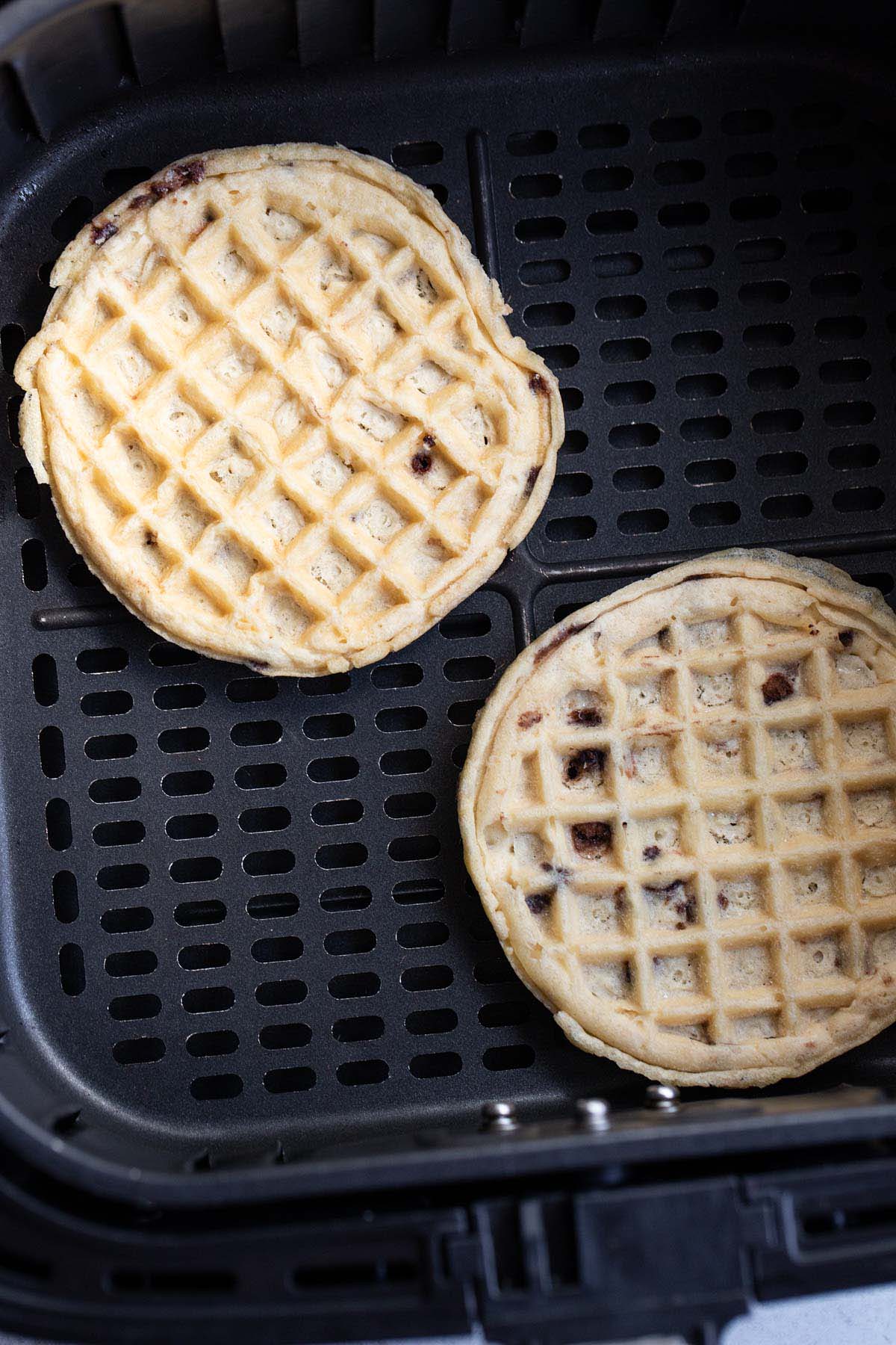 Uncooked waffles in air fryer basket.