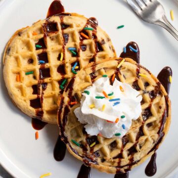 Waffles with whipped cream, chocolate syrup, and sprinkles.