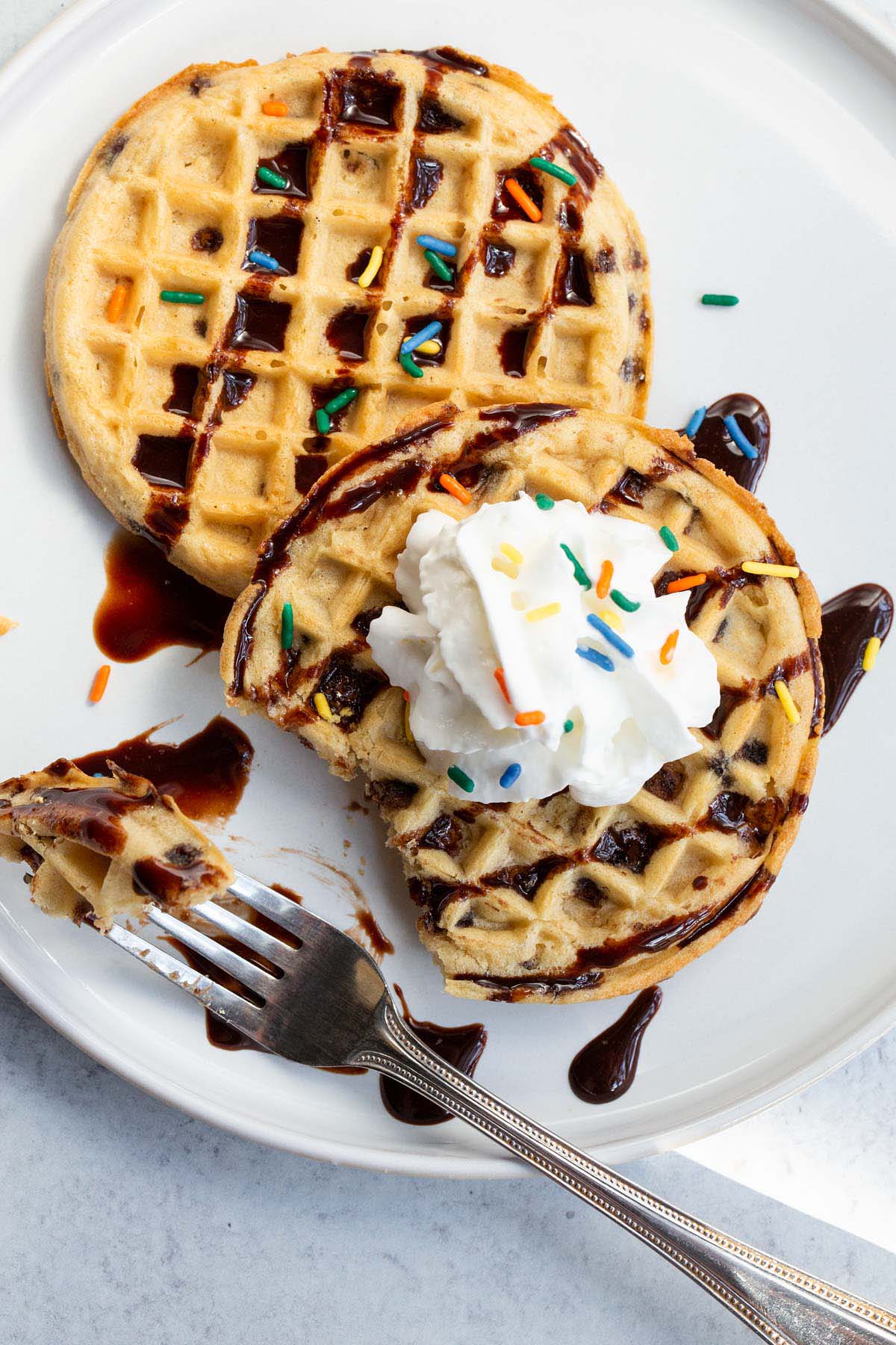 Waffles with whipped cream, chocolate syrup, and sprinkles.