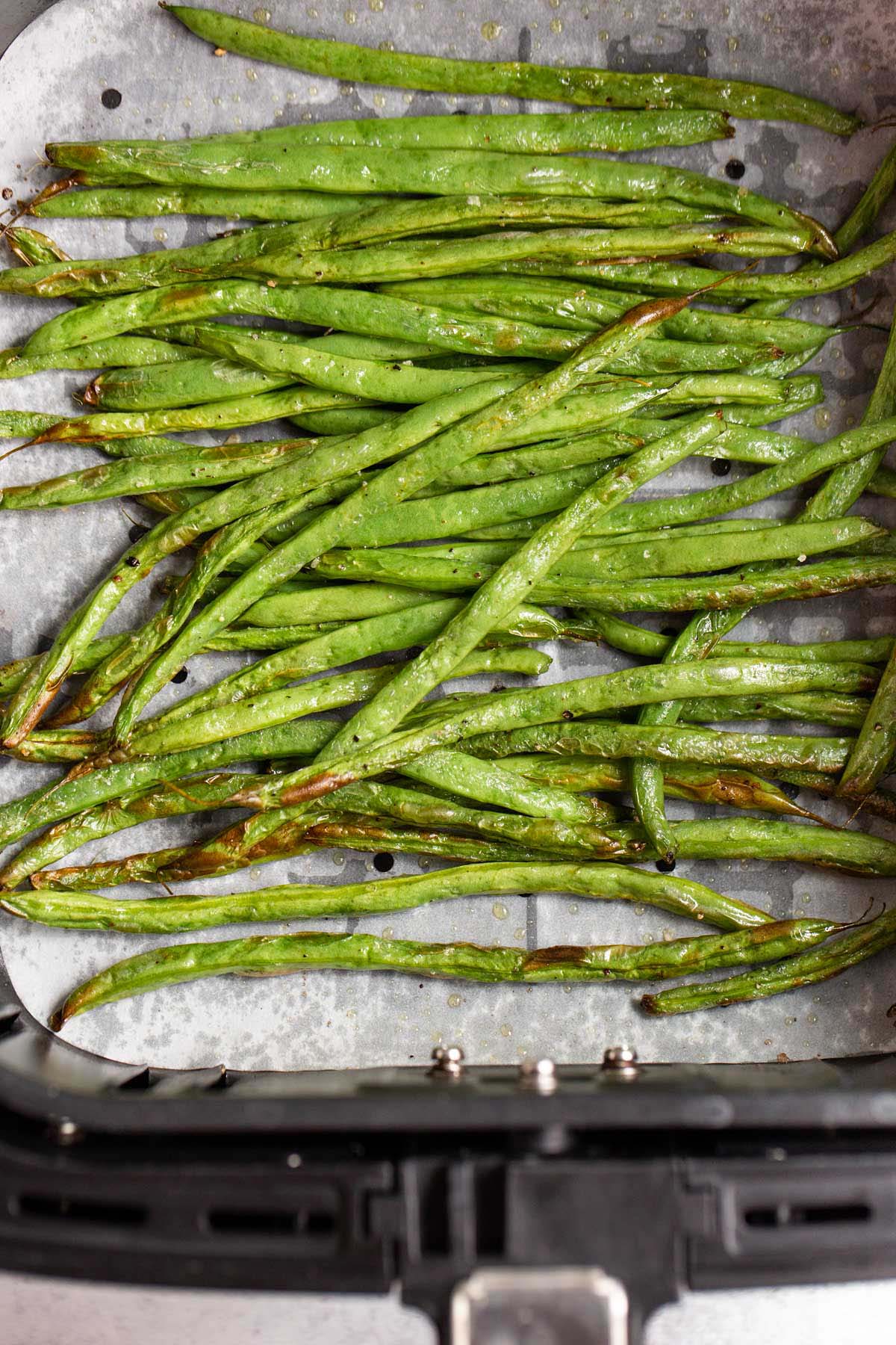 Air fried green beans in air fryer basket.