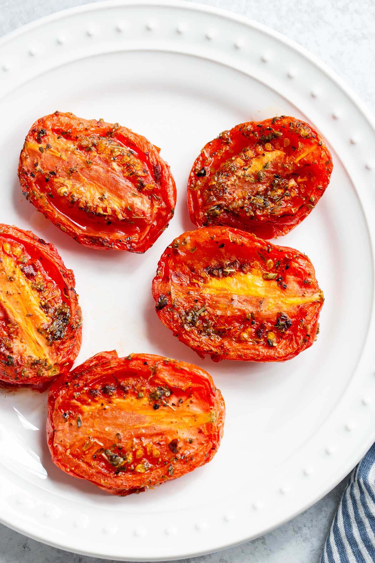 Air fried roma tomatoes on a white plate.