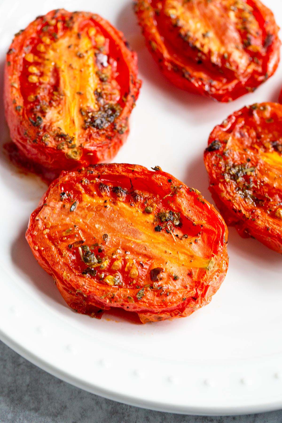 Air fried roma tomatoes on a white plate.