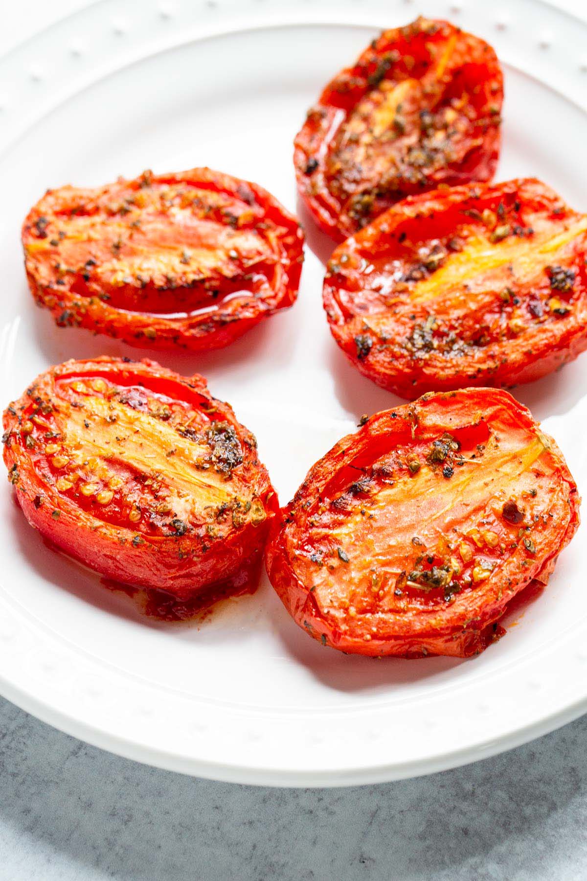 Air fried roma tomatoes on a white plate.