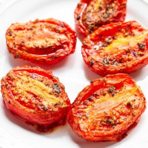 Air fried roma tomatoes on a white plate.
