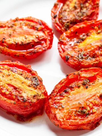 Air fried roma tomatoes on a white plate.