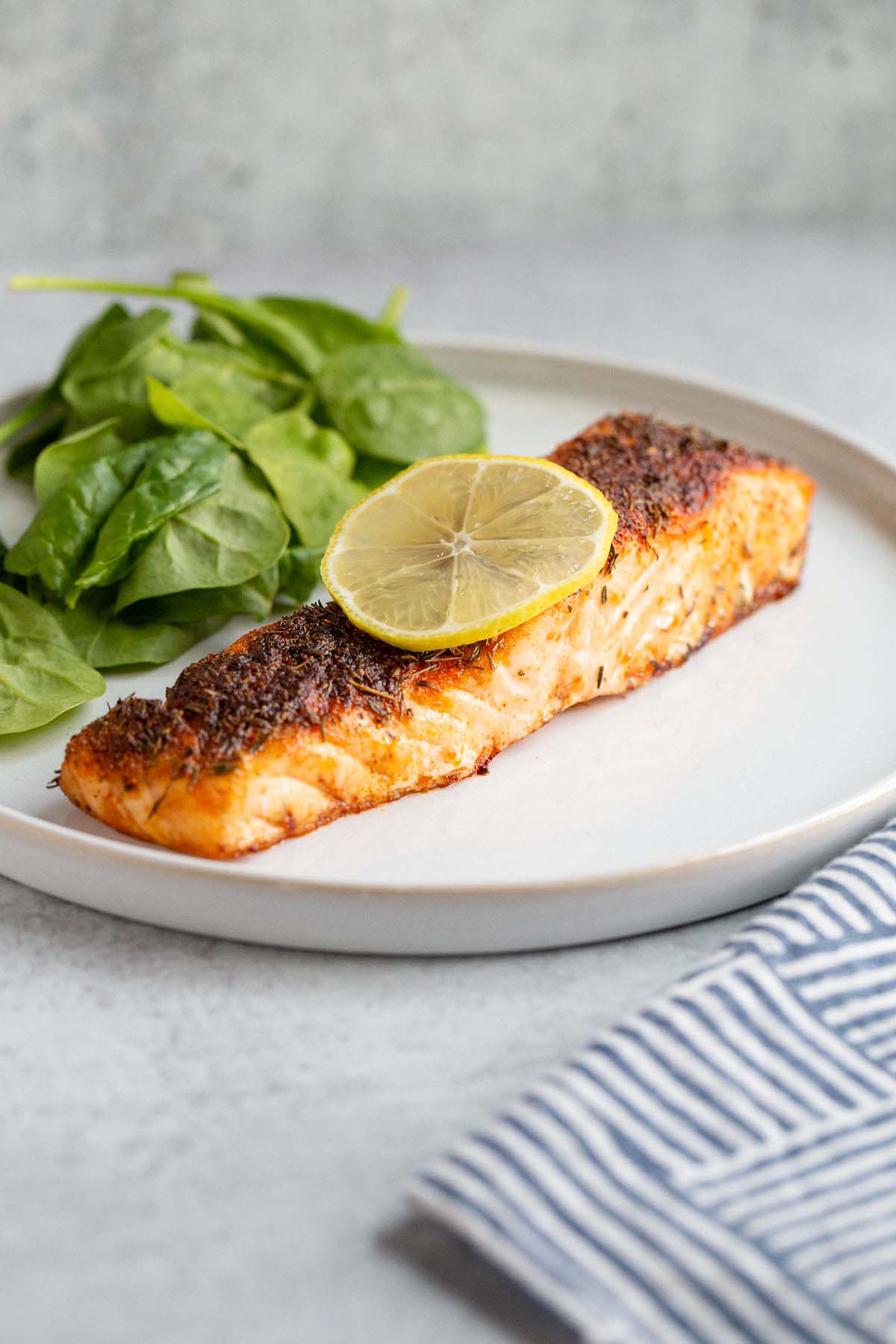 Air fried salmon on a plate with a lemon slice.